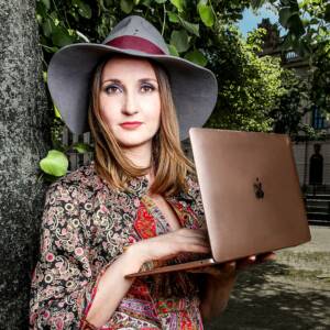 Frau steht und hÃ¤lt einen Macbook in der Hand