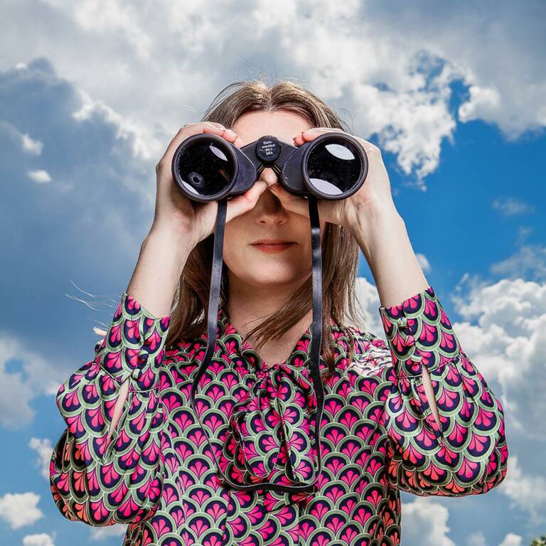 Woman looks into the distance with binoculars