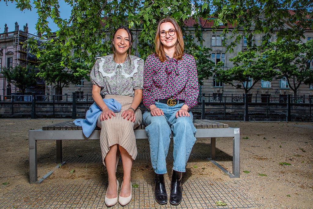 Two women sitting next to each other on a bench
