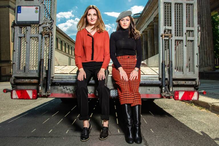 two women sitting on a truck bed