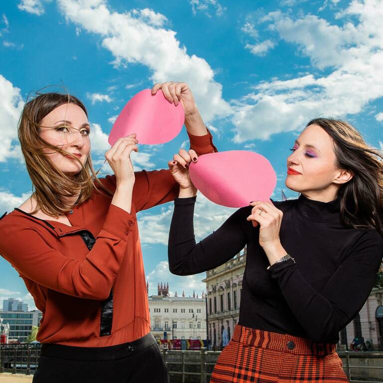 Two women holding notecards in the air